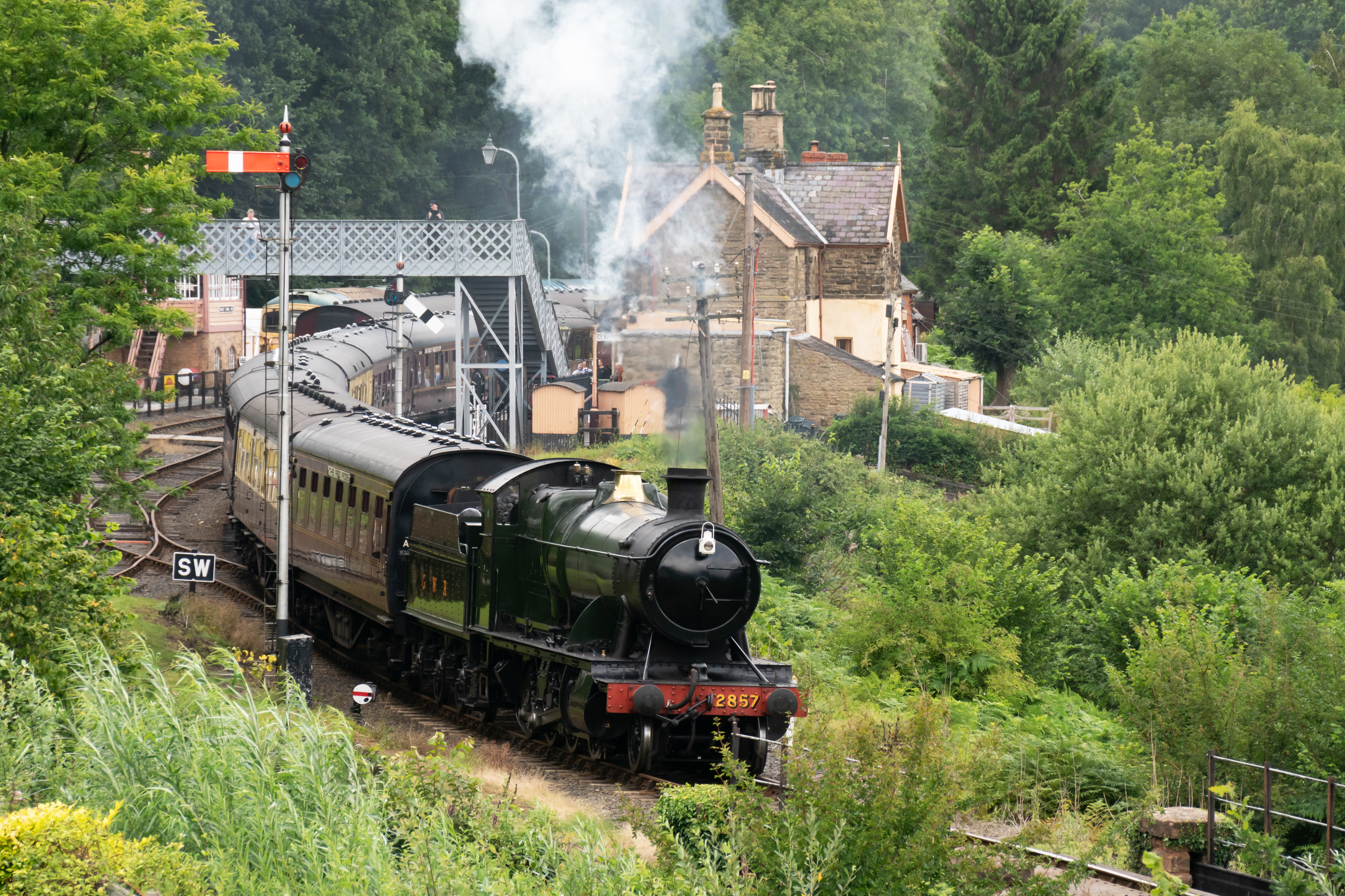 Locomotive 2857 pulling a series of carriages leaving the heritage station
