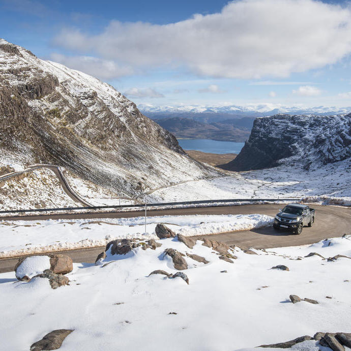 Un'auto su una strada di montagna circondata dalla neve