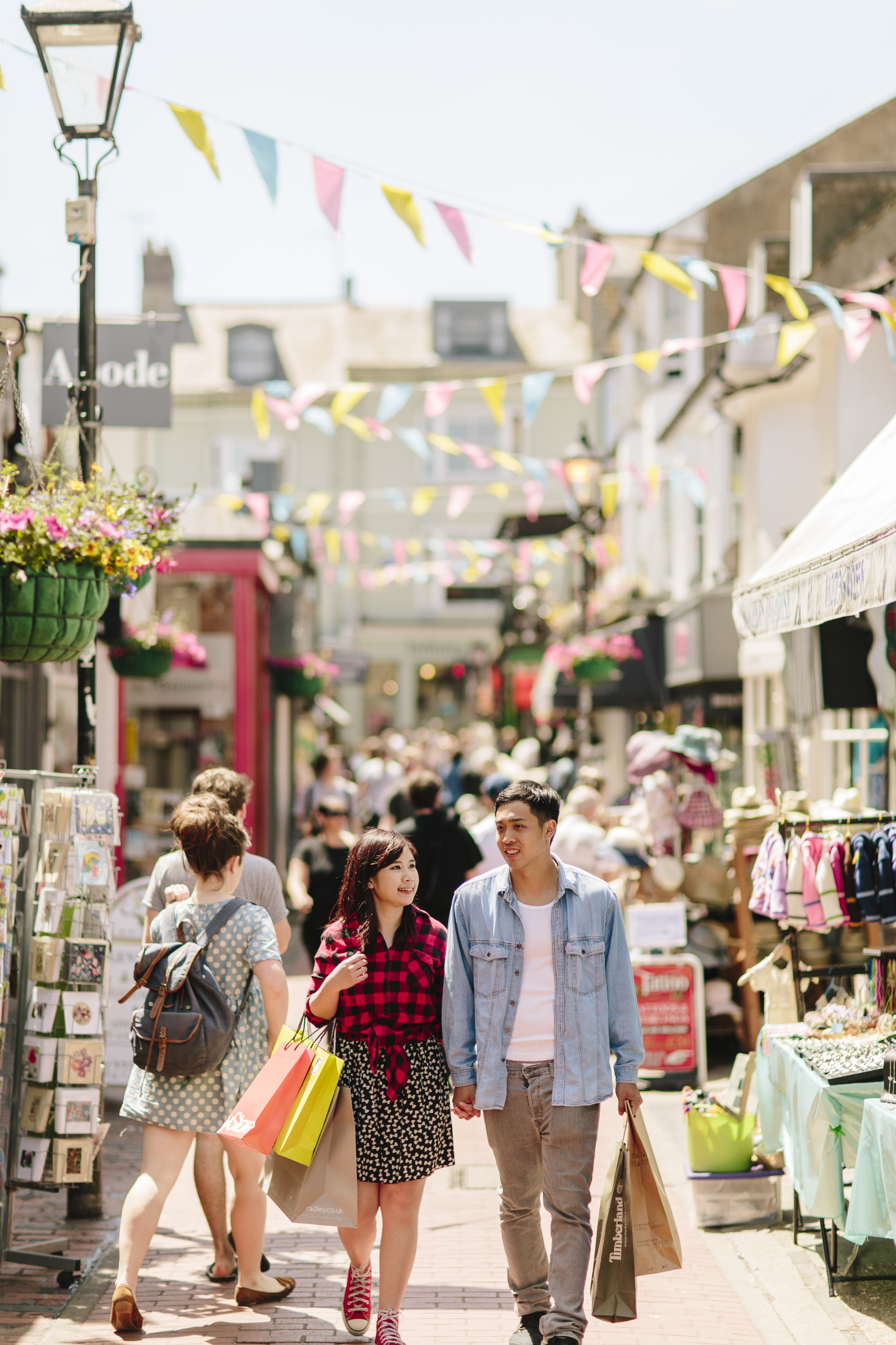 Couple holding hands, walking through a busy pedestrian street with stalls and shops either side