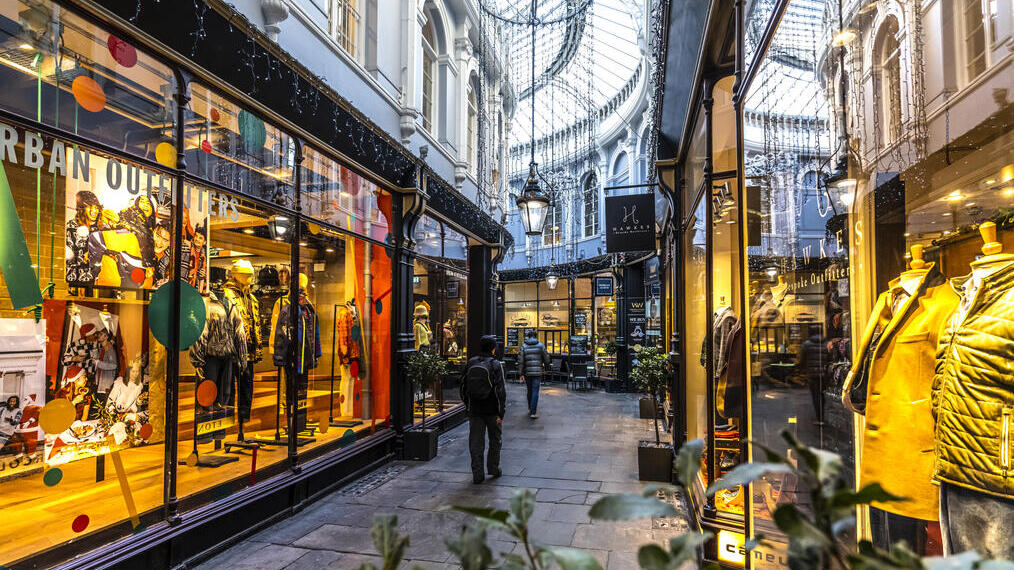 People walking between shops in an arcade, lit up from inside