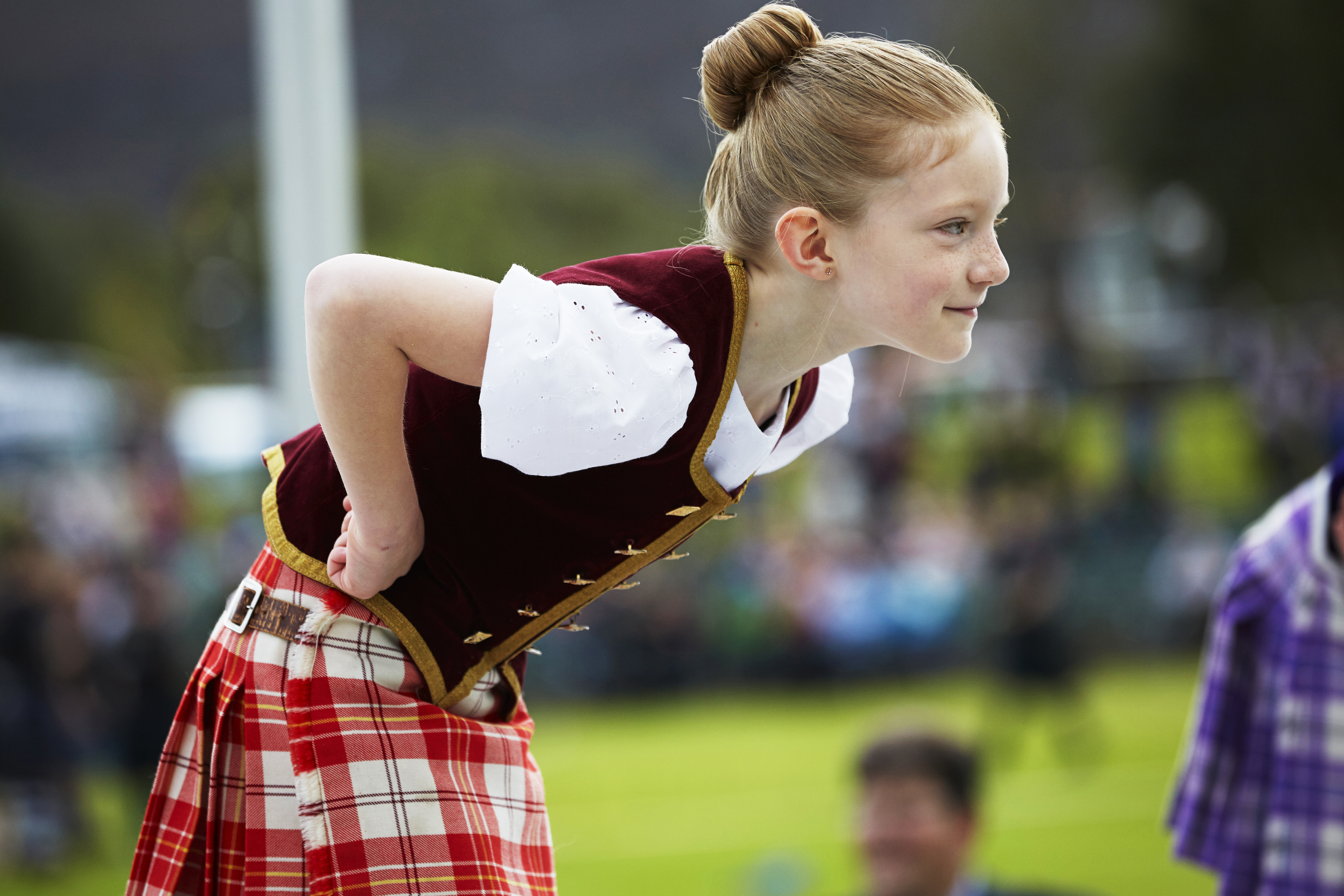 Niño con falda escocesa inclinado hacia delante