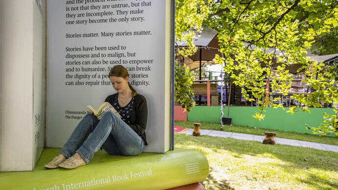 Frau, die bei einem Buchfestival sitzend liest