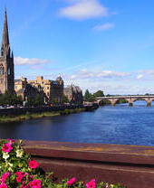 A view across a wide river to a church in the summer