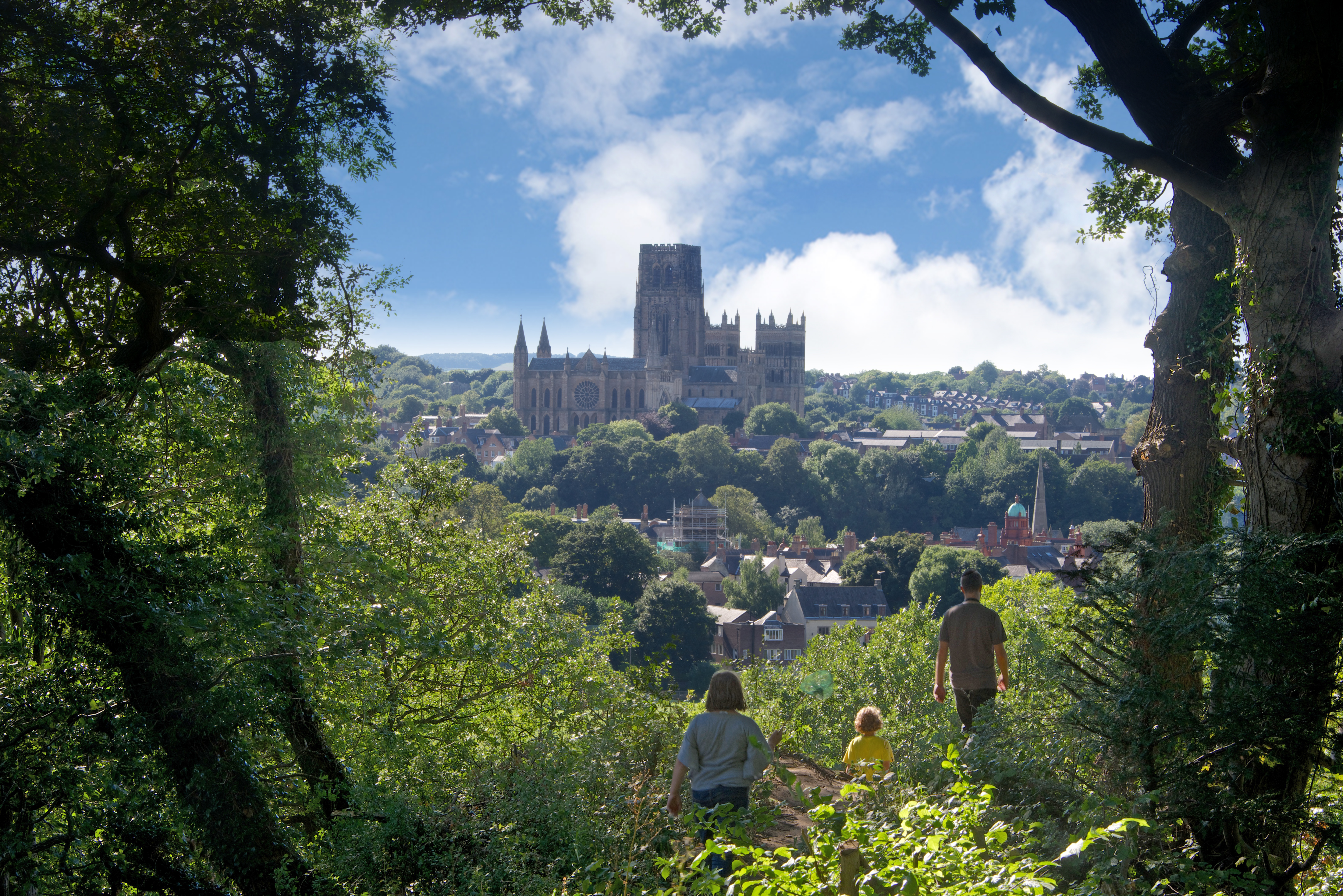 Family walking on a hill top looking down on to Durham Cathedral