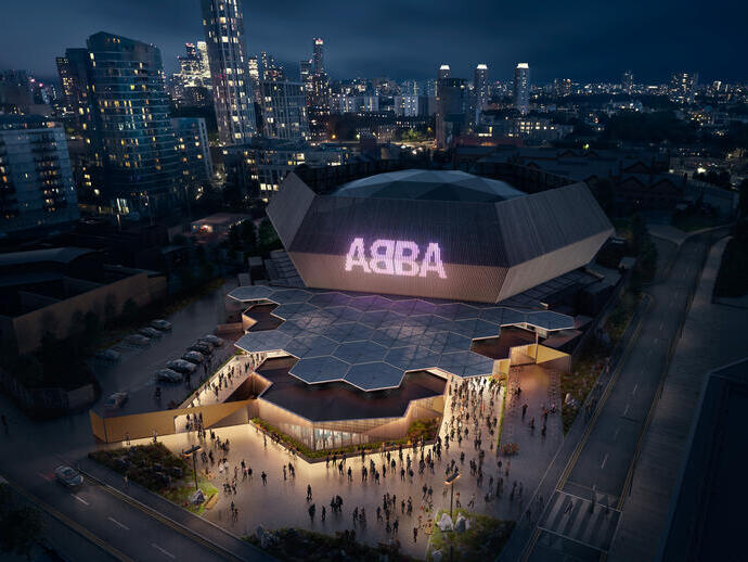 Aerial promotional image for ABBA Voyage of large venue at night with ABBA sign lit up and people at entrance