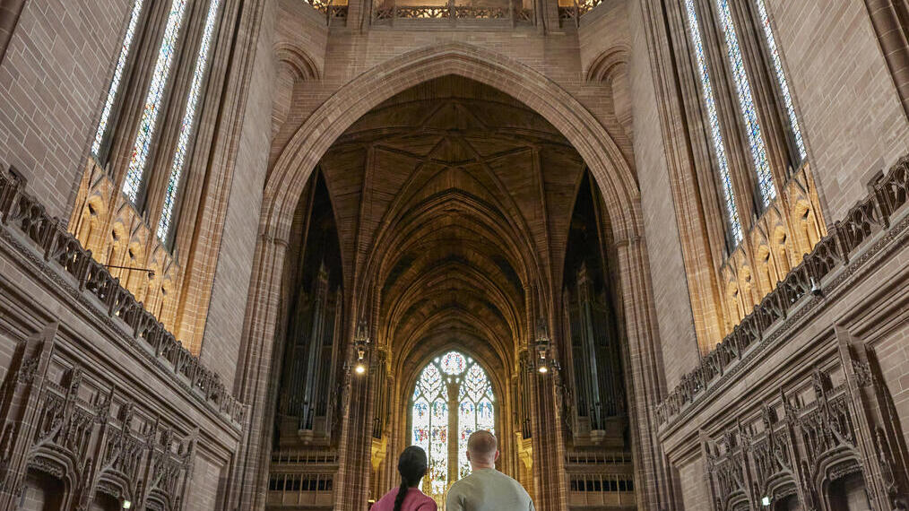 Two people take a tour of an Anglican Cathedral.