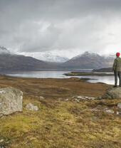 Homme debout sur un rocher contemplant le paysage avec les montagnes au loin