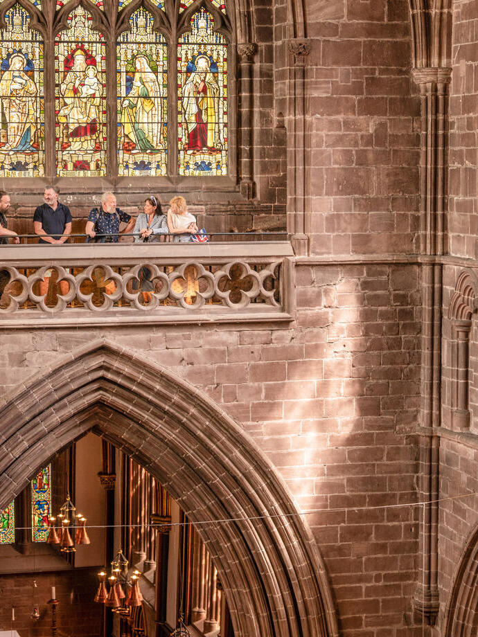 A group of people stand in a viewing platform inside a Cathedral.