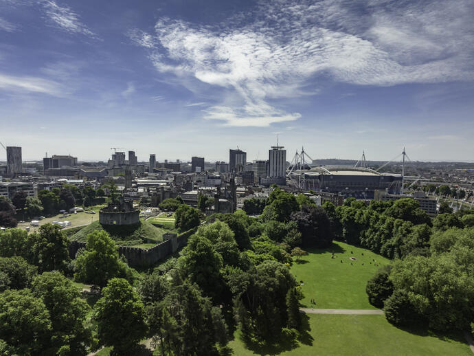 View of Bute Park, Cardiff from above, with green trees in the foreground and blue skies
