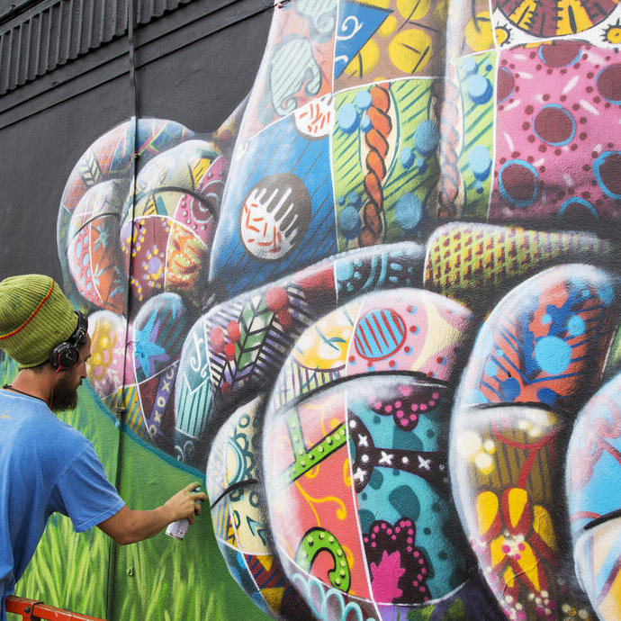 An artist using spray paint to design a piece of street artwork.