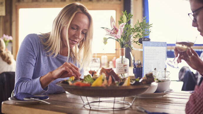Blond woman and man sitting at table, eating seafood platter