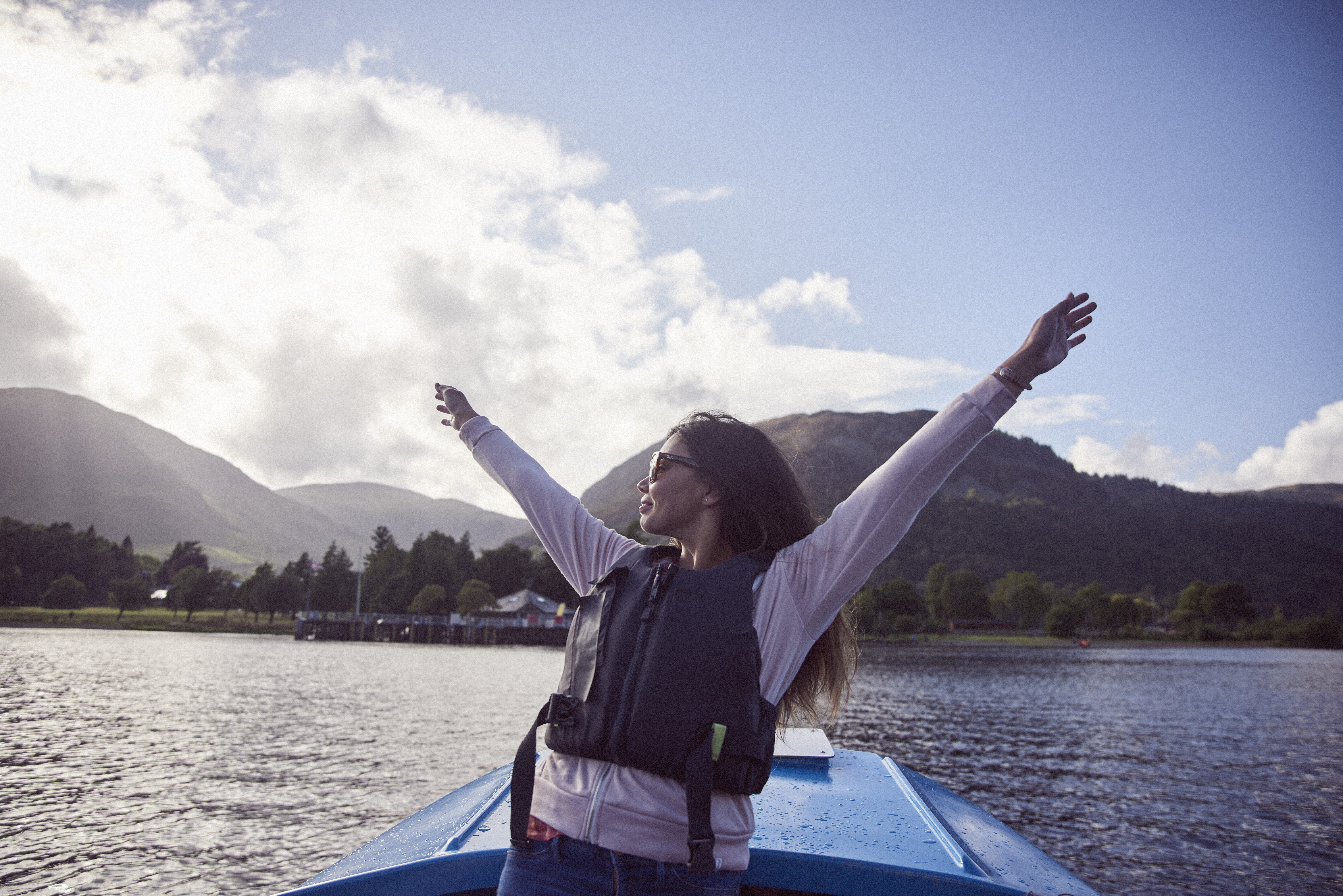 Woman with outstretched arms on a boat on a lake