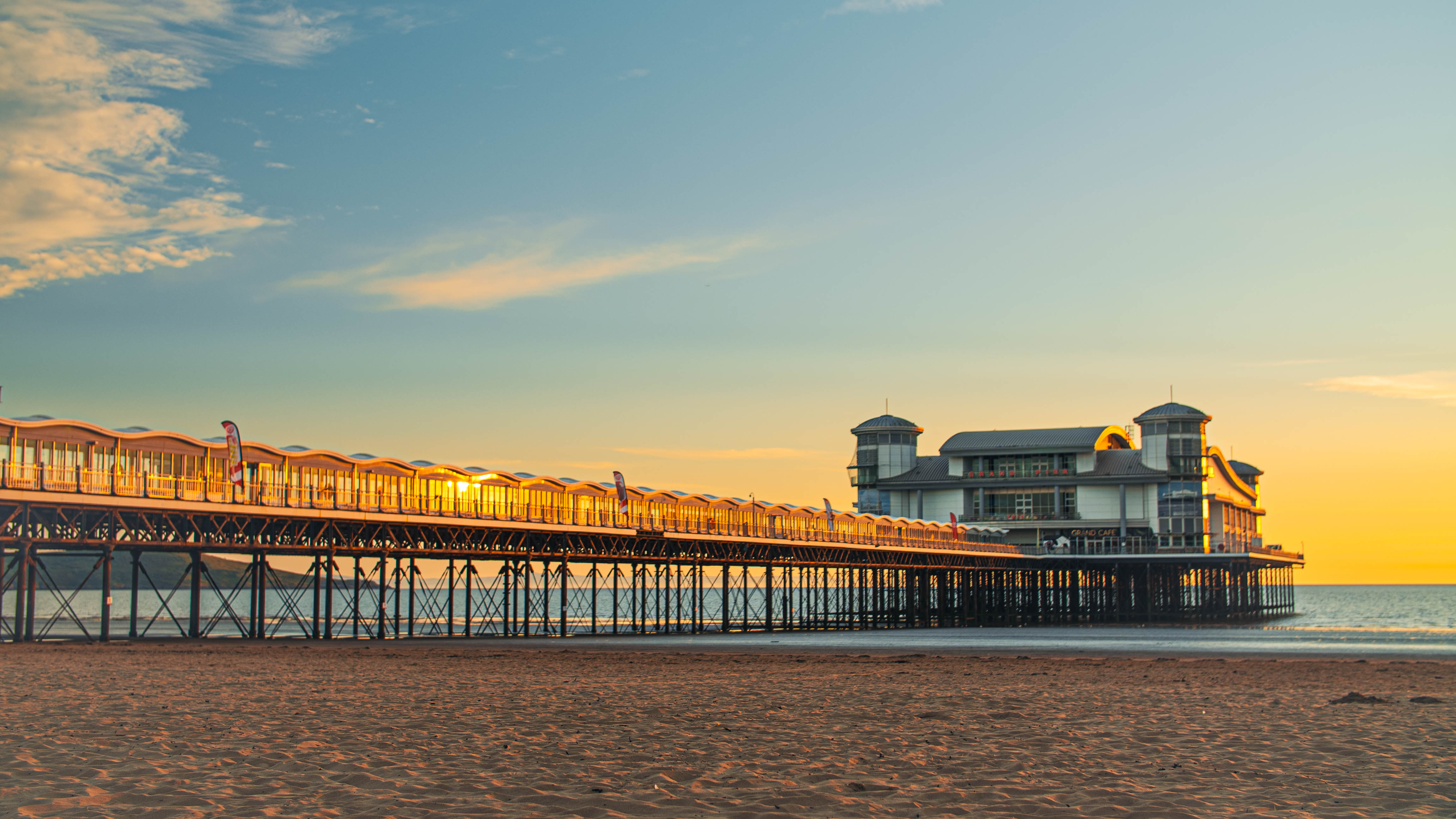 A majestic pier stretching out into the ocean with the tide out at sunset.