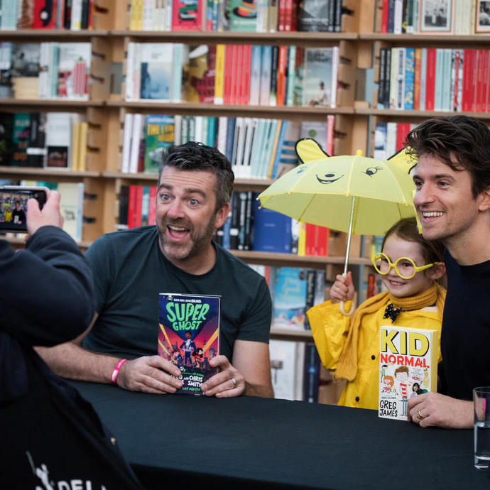 Two men holding books and posing with a child