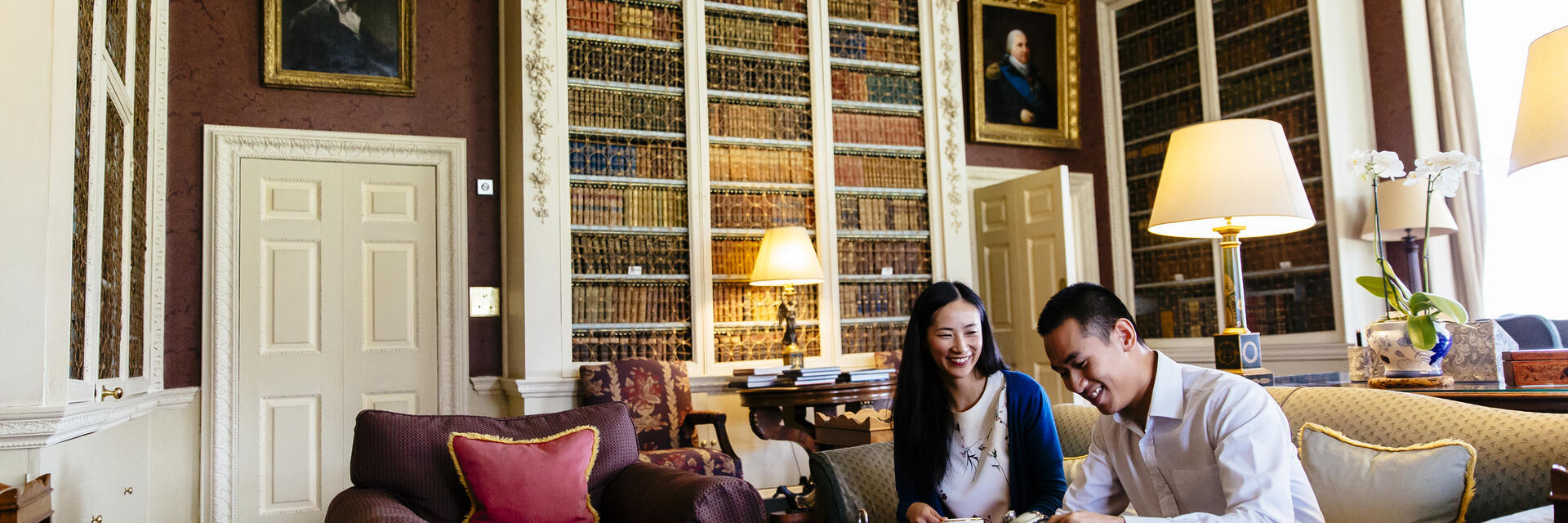 An asian couple, sitting on a sofa, having afternoon tea