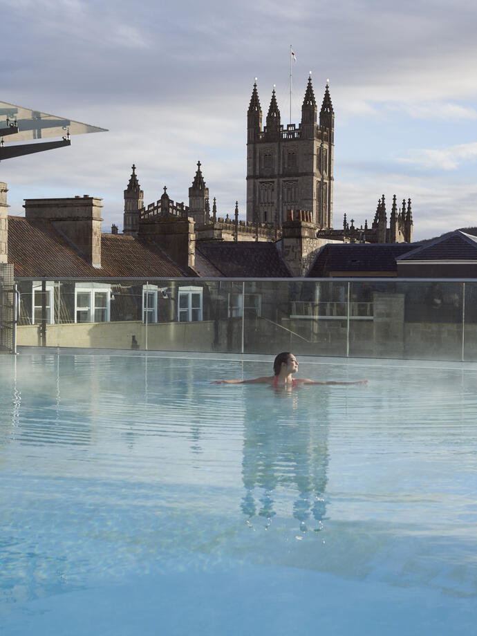 Woman in a roof top swimming pool at a spa