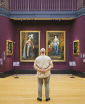 Rear view of man standing looking at portraits in a gallery