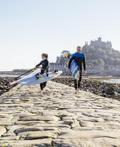 Windsurfers walking on a stone causeway that links an island to the mainland