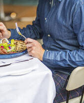 Un hombre sentado en la mesa de un restaurante con una ensalada de embutidos y un cóctel.