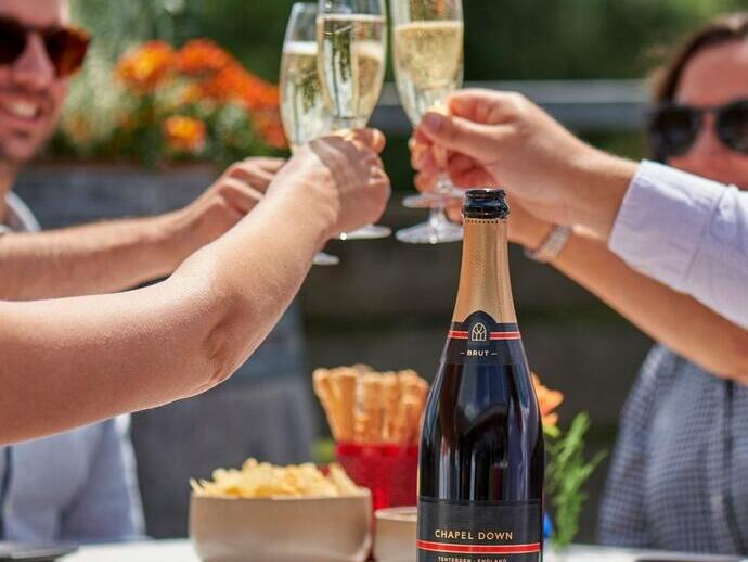 Un gruppo di persone sedute a un tavolo che brindano alla Chapel Down Winery