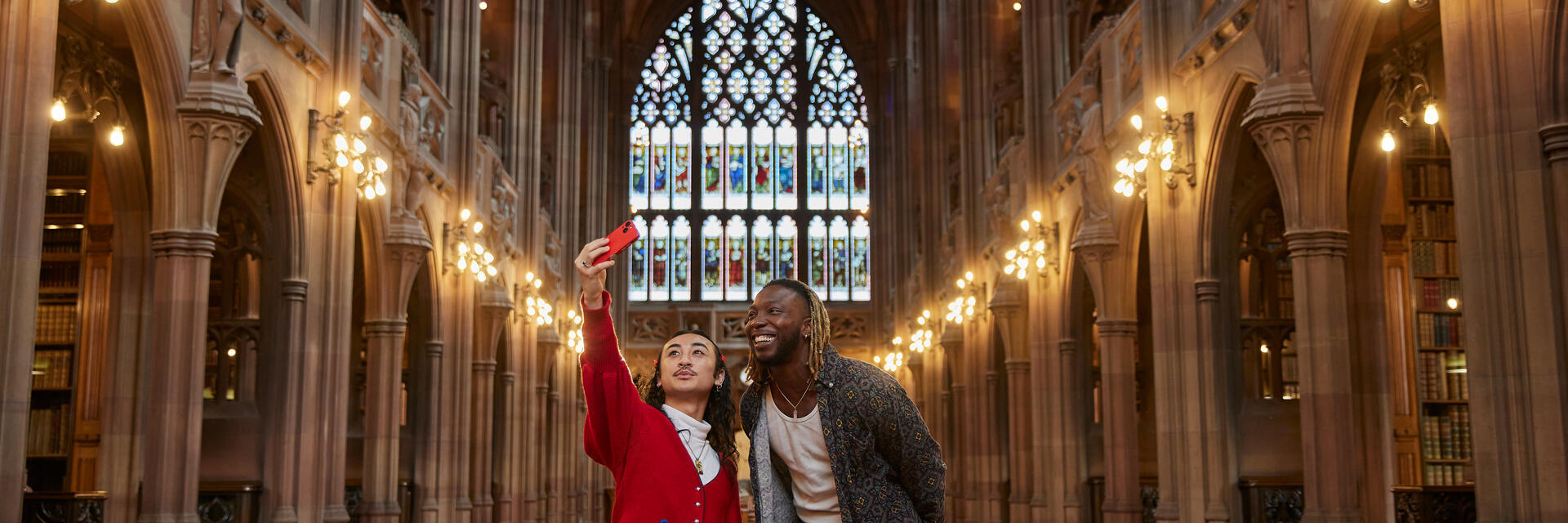 Due uomini che si scattano un selfie all'interno di una grande biblioteca.