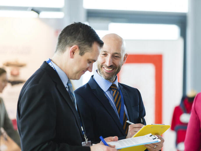 Two men in formal attire, filling out forms