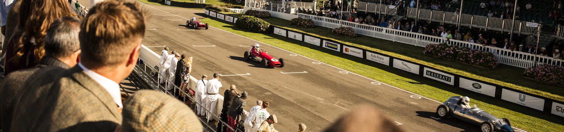People in a grandstand watching a vintage sports car race
