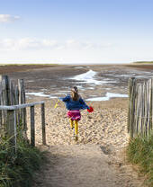 Una niña corriendo por un sendero hacia la playa de Holkham