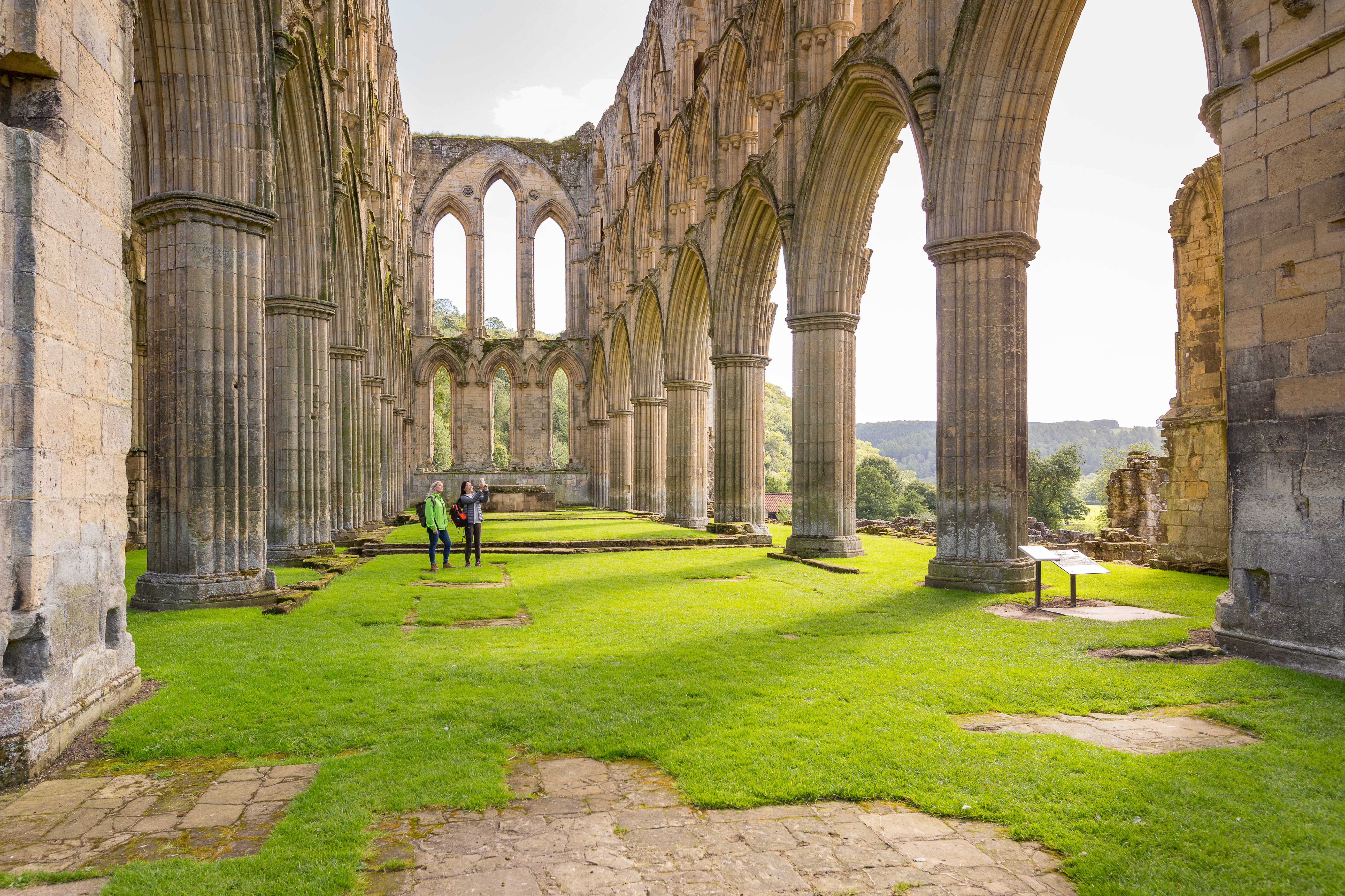 Two female friends in the central nave of a ruined abbey in the sunshine