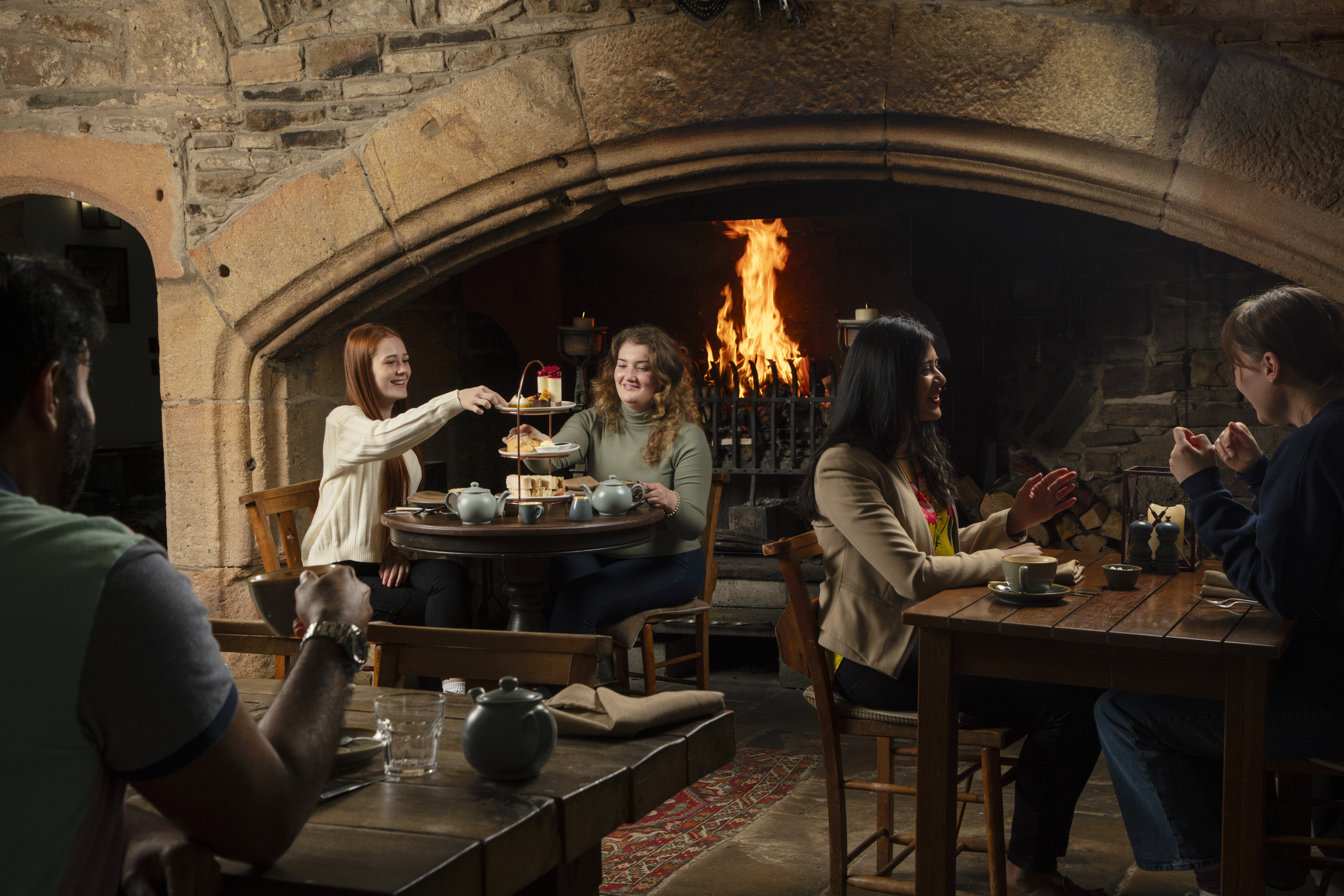 Dos mujeres disfrutan de un té de la tarde frente a la chimenea en un pub histórico tradicional