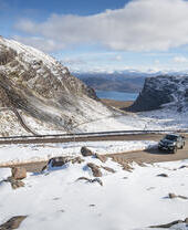 A car on a mountain road surrounded by snow