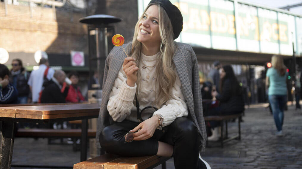 Une femme assise sur un banc, souriante, tenant une sucette