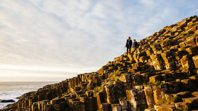 Man and child standing on rock formations by the sea