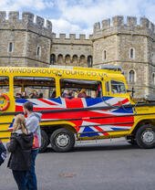 A Windsor Duck Tours amphibious vehicle drives past Windsor Castle.