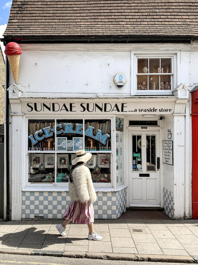 Young woman walking in front of seaside ice cream shop