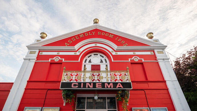 Outdoor facade of an old red retro cinema.