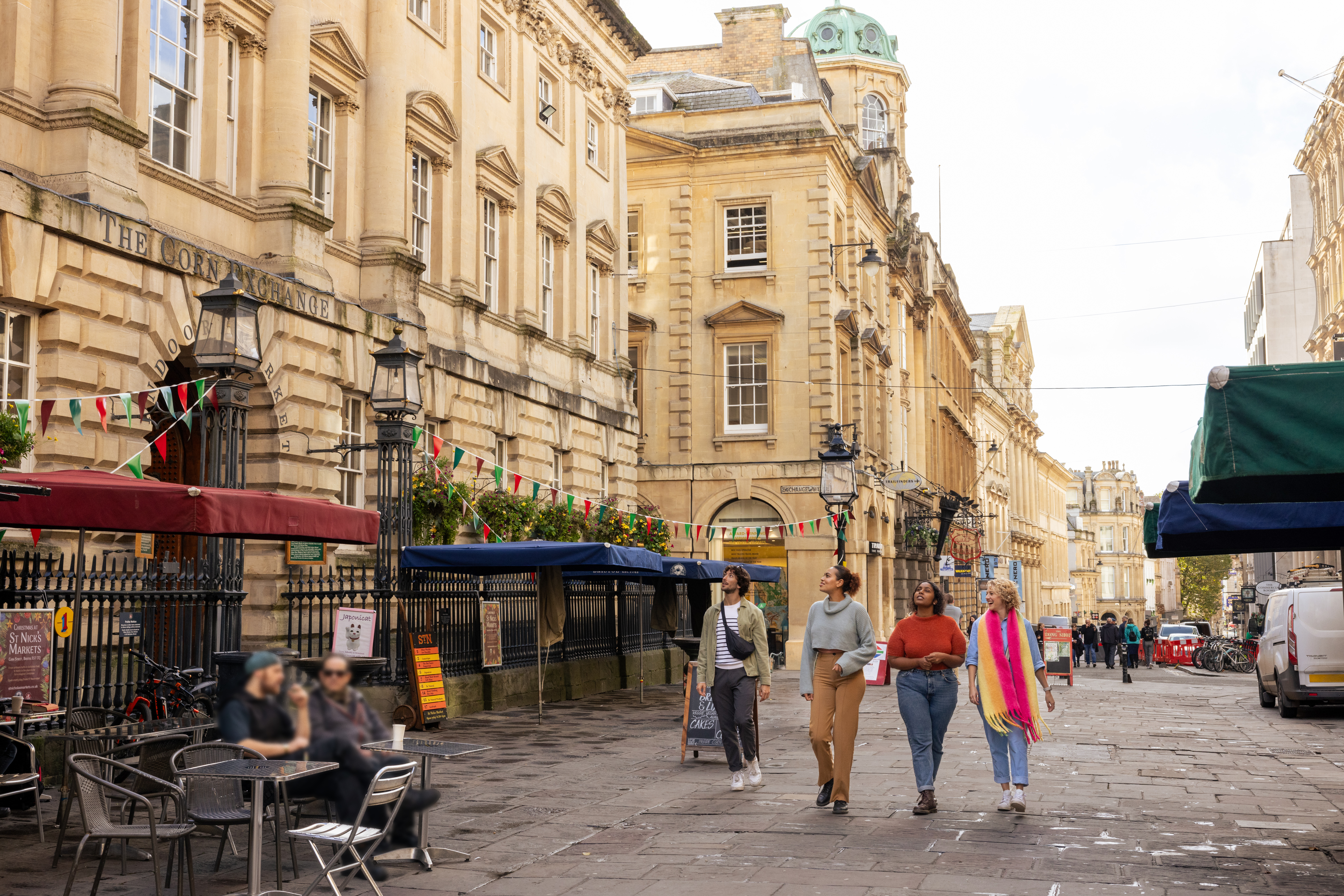 Friends walking in front of old historic buildings, on a cobbled street.