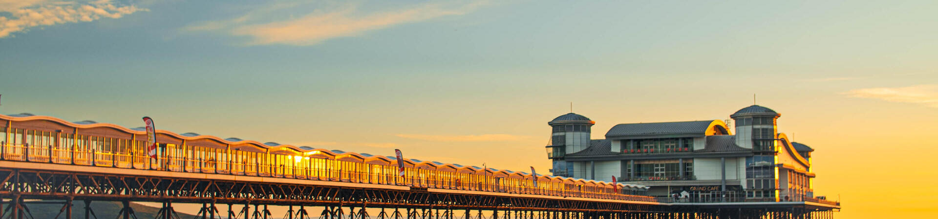 A majestic pier stretching out into the ocean with the tide out at sunset.