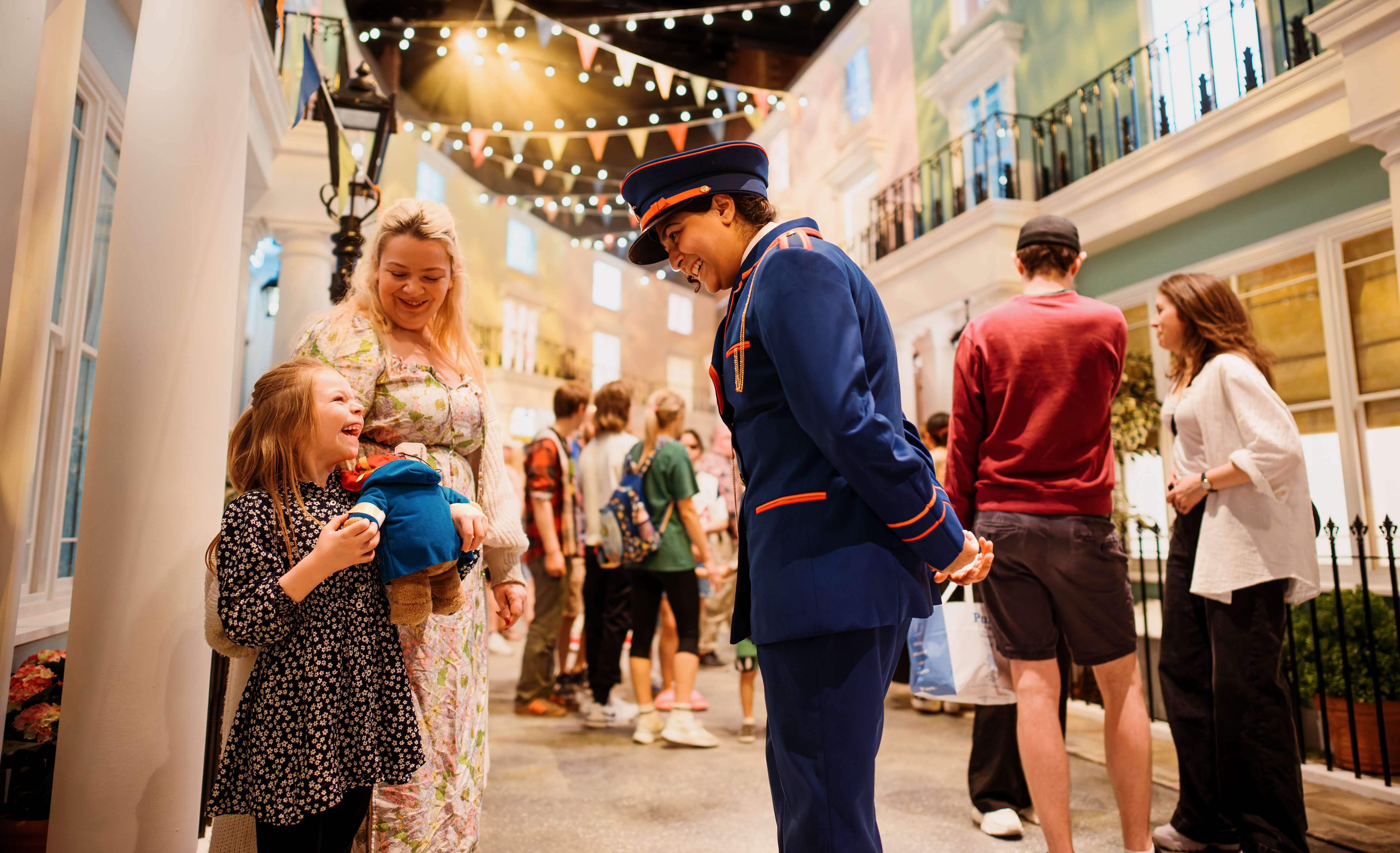 Character actors talking to a young child on the set of a stage.