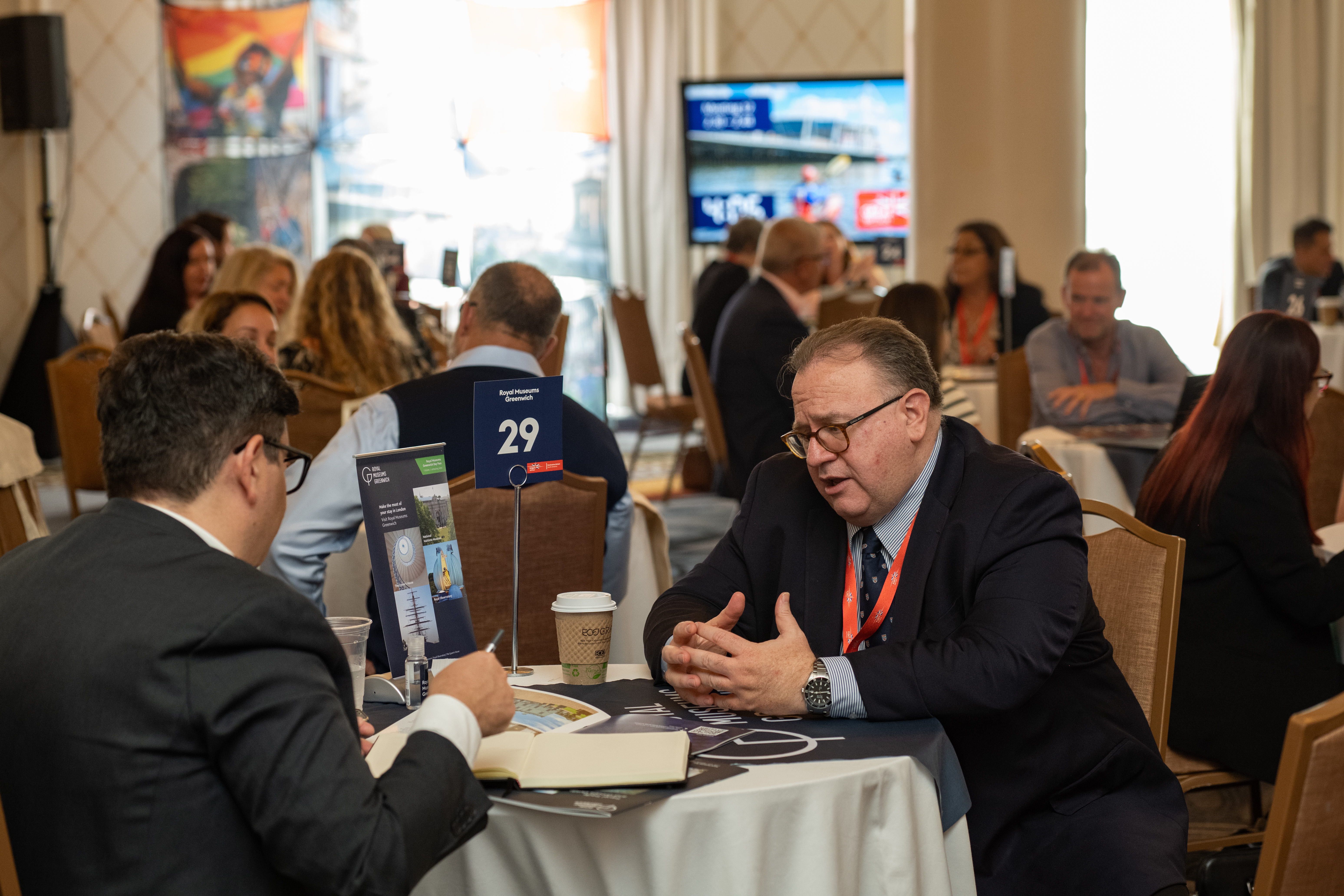Attendees of an event sit at a table and talk