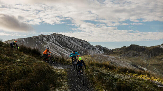 Friends mountain biking through the top of rugged mountain ranges.