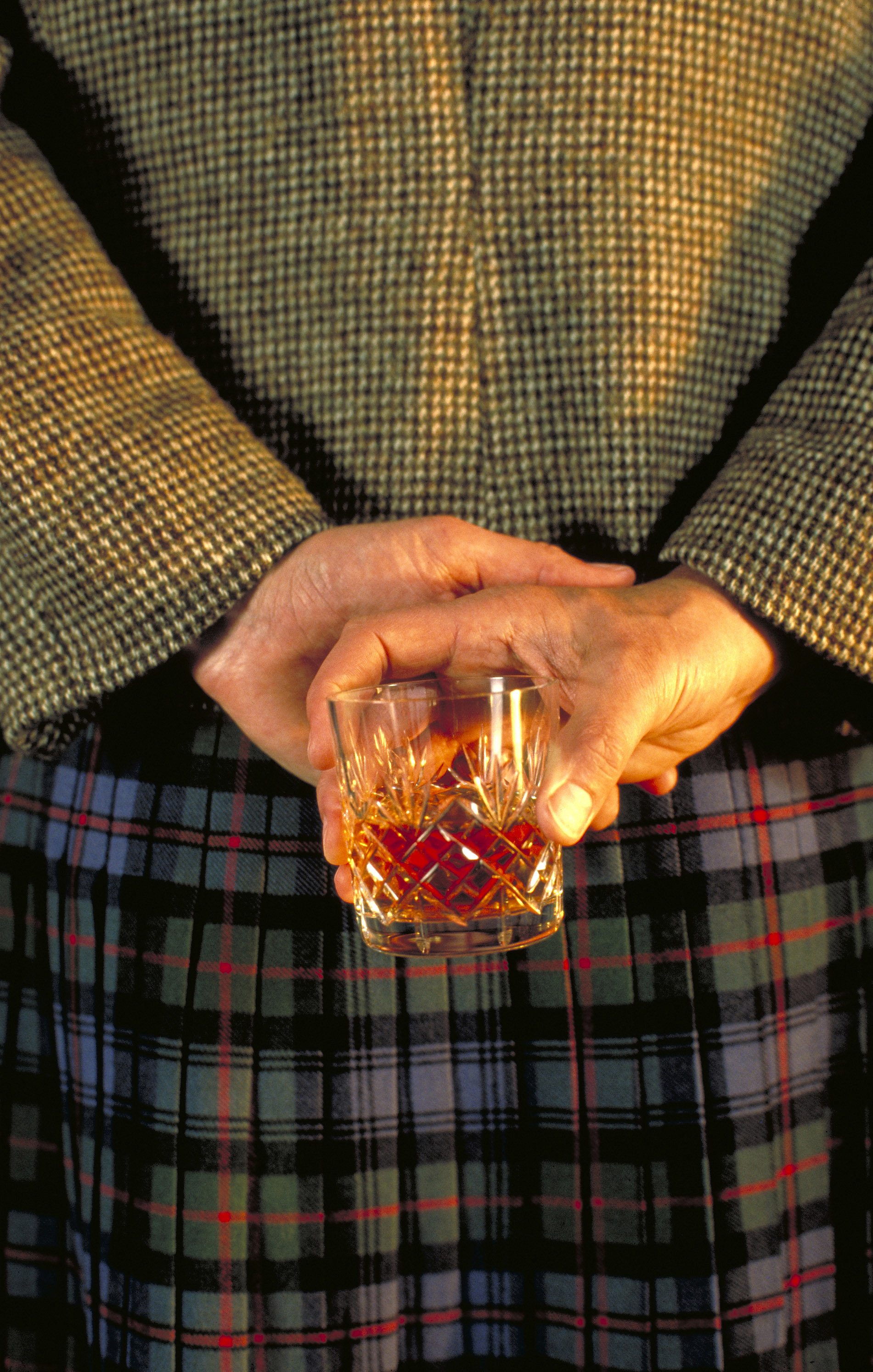 Scotsman with glass of whiskey held behind his back