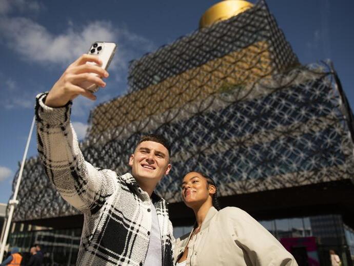 Couple taking a selfie on a phone in front of a modern building