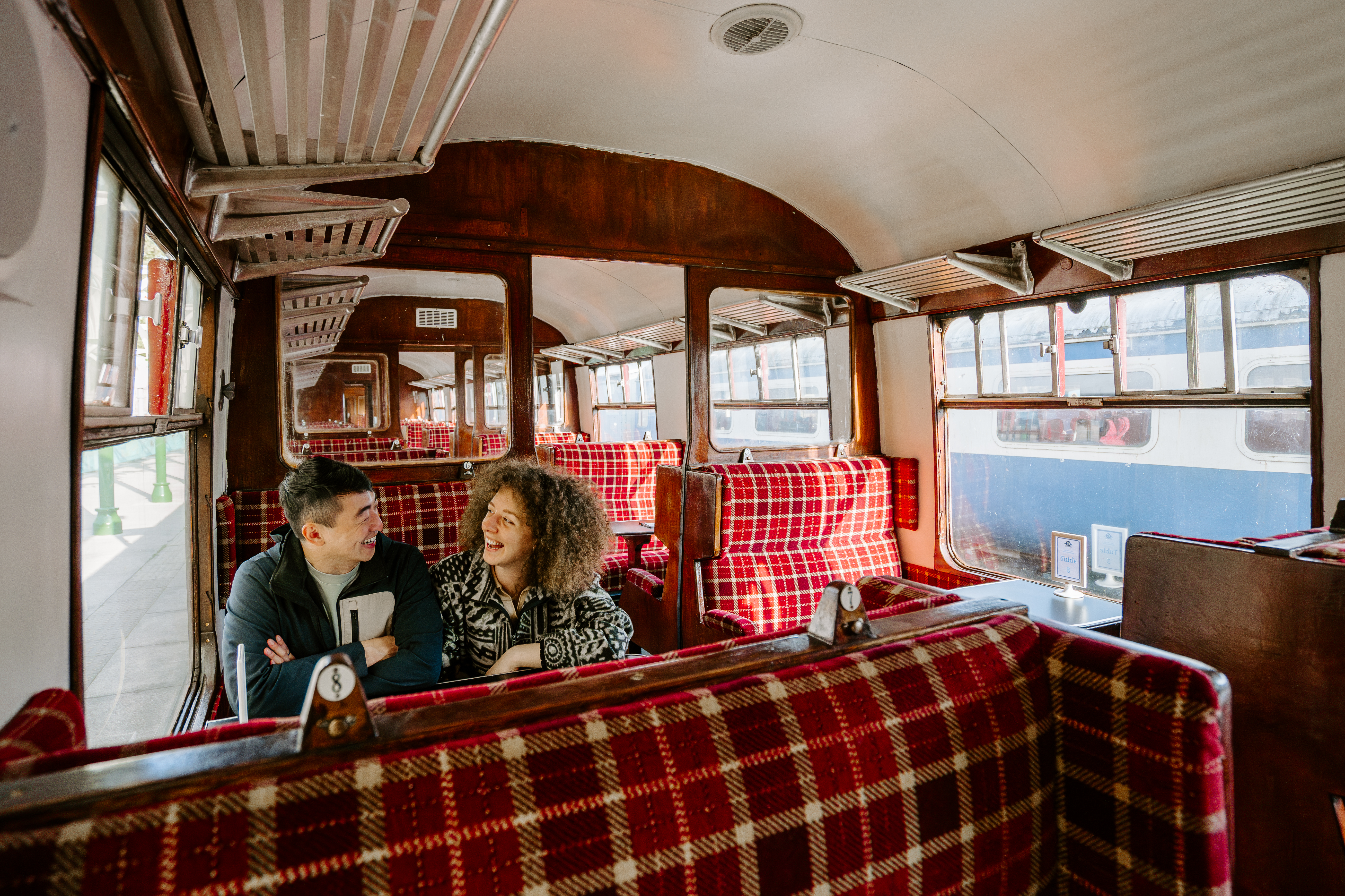 A man and a woman sitting together inside a train carriage.