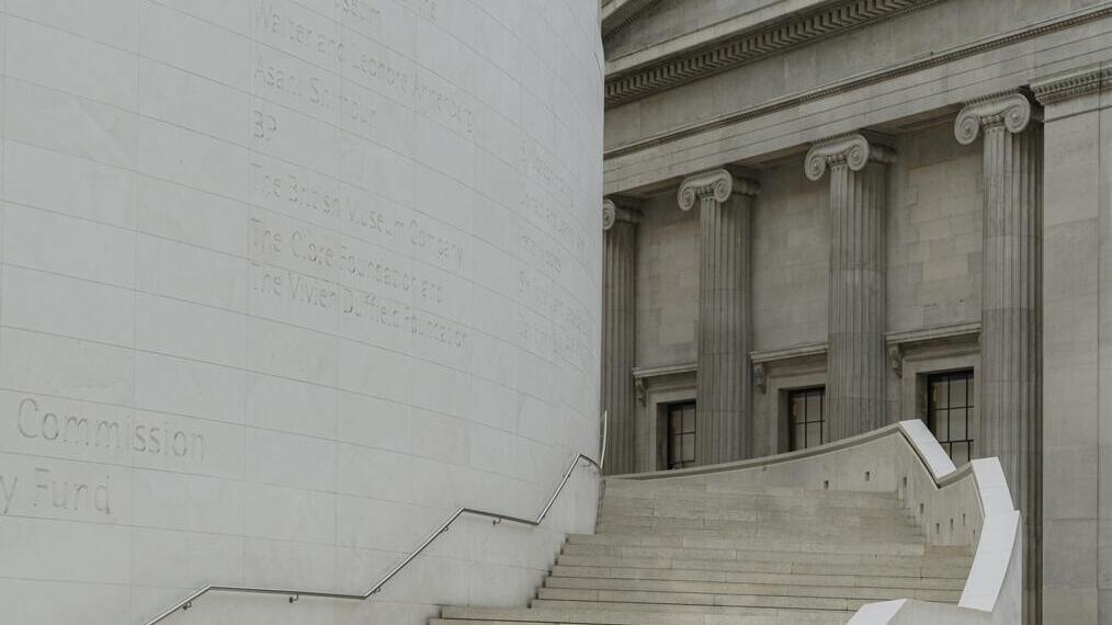 Woman walking up a wide staircase under a geometric glass ceiling