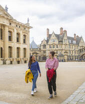 Zwei Frauen spazieren durch einen Innenhof zwischen historischen Gebäuden