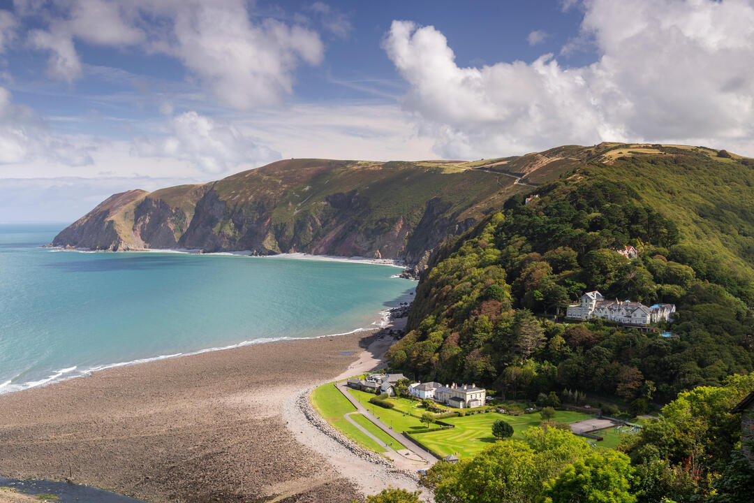 A gorgeous panorama of a turquoise bay with mountains and stately mansions.