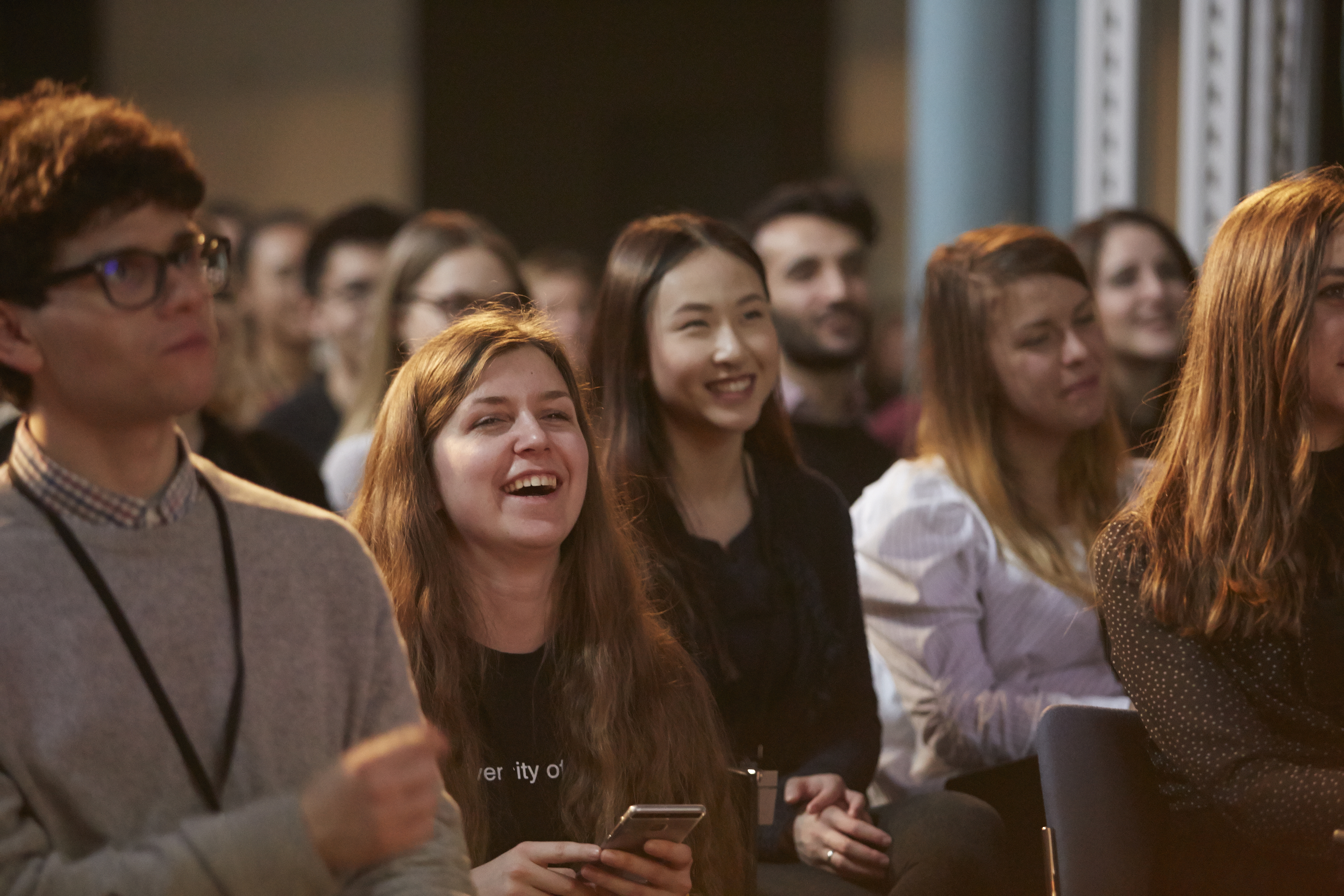 Group of people sat at event, smiling