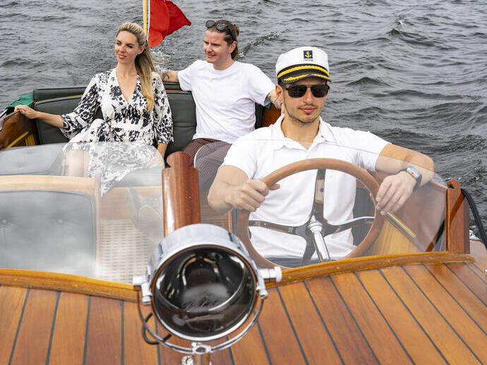 Un hombre y una mujer en un barco conducido por un patrón en un lago