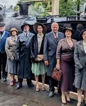 Actors in costume in front of a steam train as part of a murder mystery performance